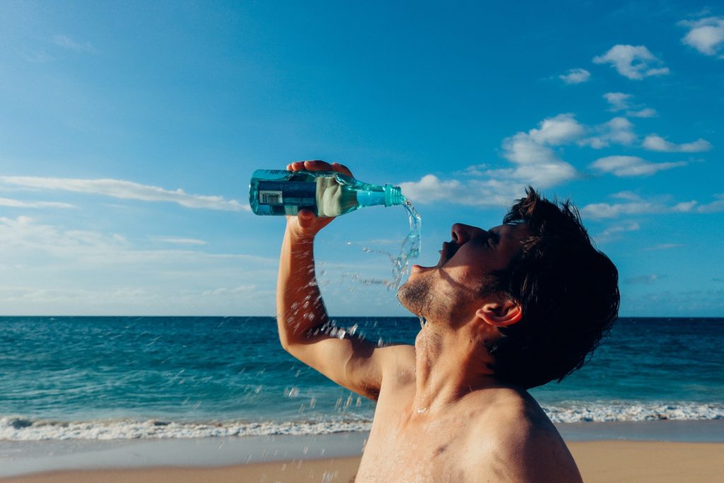 uomo in spiaggia che beve acqua