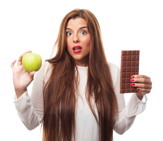 donna con in mano una mela e una tavoletta di cioccolato