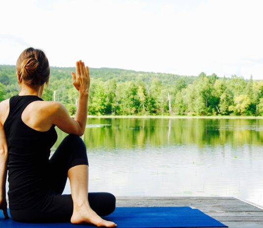 donna in posizione yoga in riva al lago