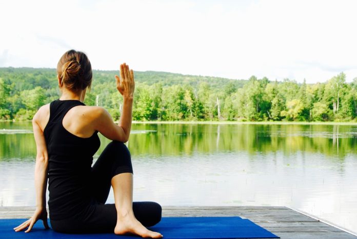 donna in posizione yoga in riva al lago